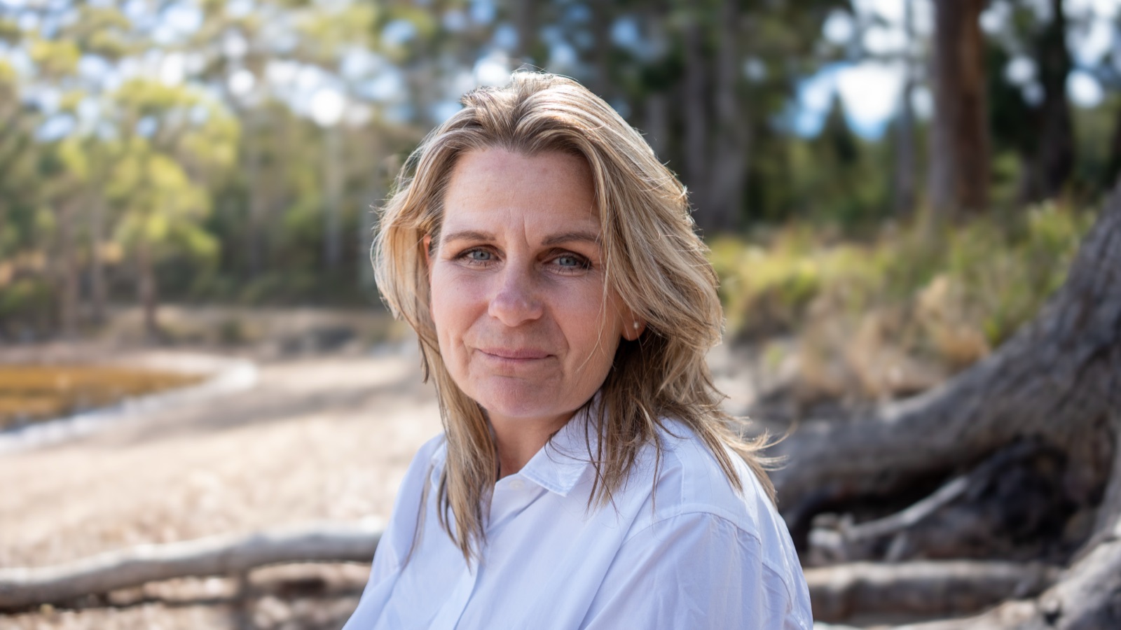 Annica Larsdotter seated on driftwood at the beach